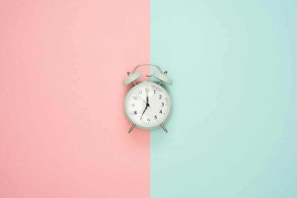 a white clock with pink and blue background